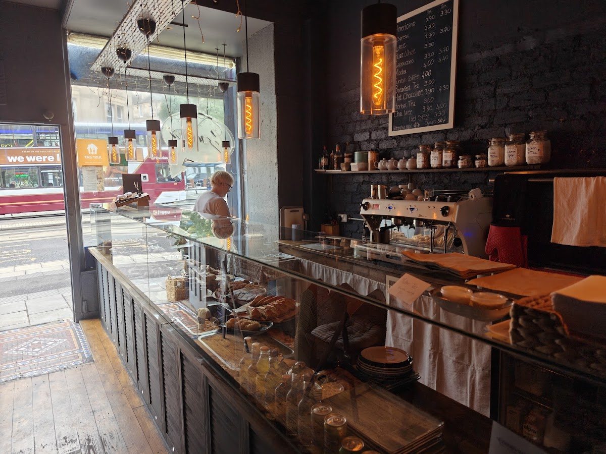 Looking along the counter to the big front window, with a tram passing on Leith Walk outside and filament lamps overhead.